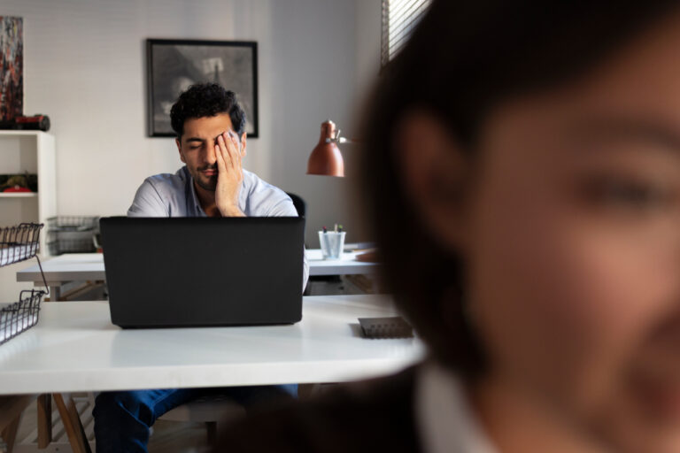 Homem estressado em ambiente corporativo, ilustrando o burnout no ambiente de trabalho.