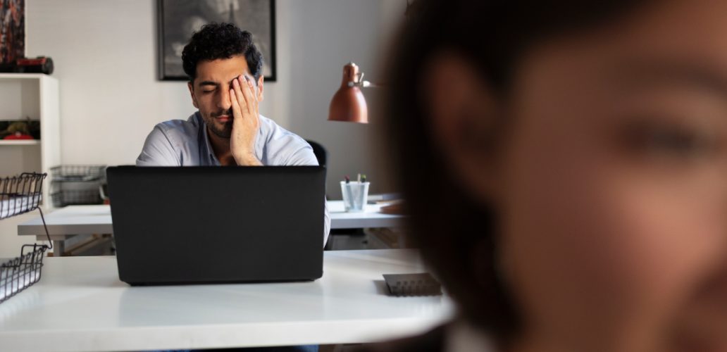 Homem estressado em ambiente corporativo, ilustrando o burnout no ambiente de trabalho.