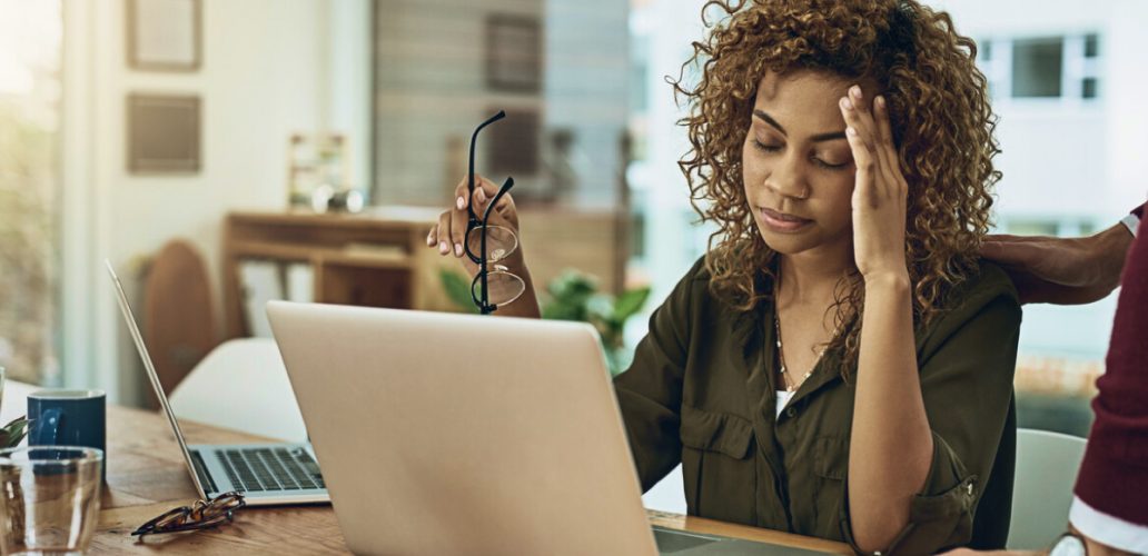 Mulher no escritório aparentando cansaço e estresse, ilustrando os impactos do Burnout na CID-11 como fenômeno ocupacional reconhecido.