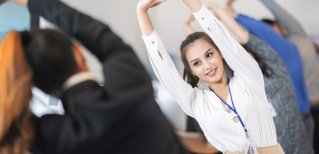 Asian office worker relax and stretching by group exercise before start working every morning in her company
