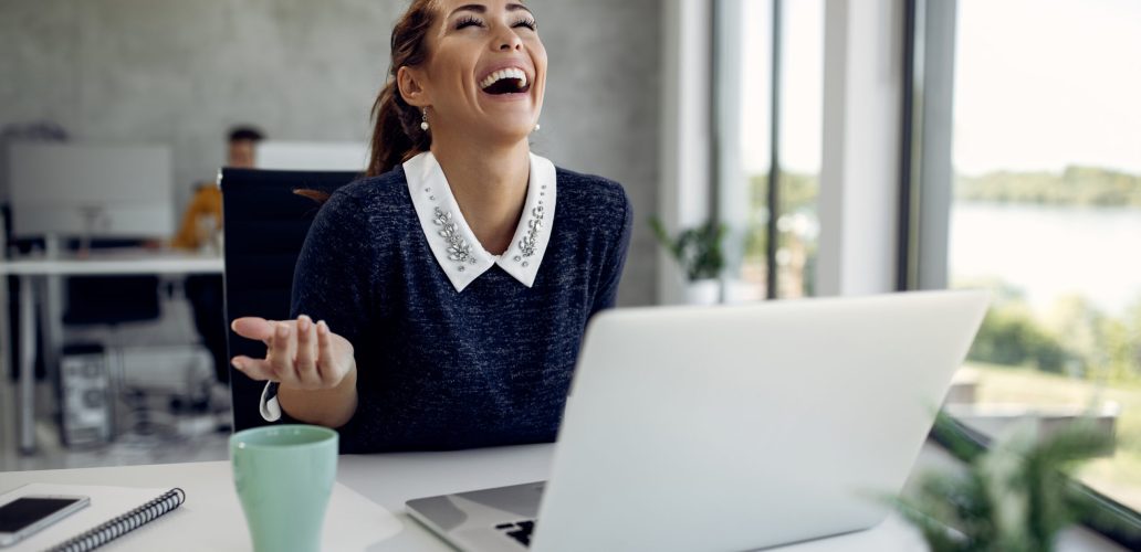Young happy businesswoman laughing while having video call over laptop in the office.